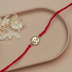 Stylized Om Rakhi for Brother – Round Gold-Tone Om Symbol Rakhi with Radiant Sun Design & Red Thread